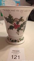 White ceramic 7 inch cachepot vase decorated with holly leaves, red berries, and the phrase "The holly and the ivy when they are both full grown."