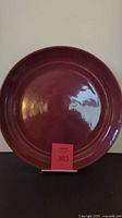Front full view of deep burgundy circular ceramic platter showing smooth glossy surface.
