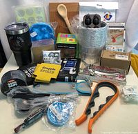 Photo showing entire assortment of new kitchen and houseware items including tumbler, spoon, cupcake molds, small tubs, coasters, and various packaged utensils.