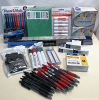 Full view of all office supplies including Paper Mate pens, glue sticks, rubber bands, markers, labels, and black stickers.