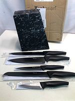 Photo of all 5 knives and the black marble design knife block showing new condition with original packaging