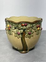 Front view of the Weller Pottery jardiniere showing apples and green leaves raised design on cream background.