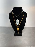 Front view of the two jade necklaces displayed on a black stand showing pendant styles and bead details.