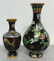 Front view of two Cloisonne vases, showing floral and dragon designs on black backgrounds with brass rims.