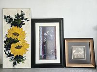 Front view showing three framed artworks: sunflower painting, vertical floral and bird print, smaller floral silhouette print