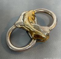 Close-up photo showing the front side of the brooch highlighting gold-tone polished detail running through two silver-tone rings.