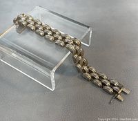 Overall view of 7.5 inch sterling silver link bracelet resting on acrylic display stand showing clasp and chain details.