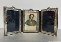 Front view of the vintage 3-panel folding photo frame showing one picture in center and two empty side panels with ornate silver borders.