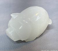 Front and side view of the white jade pig figurine showing the smooth polished surface and carved details including ears and snout.