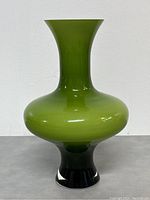 Front view of a lime green art glass vase with black base, showing smooth glossy surface and shape