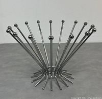 Side angled view of the stainless steel fruit bowl showing the radiating rods and round ball tips.