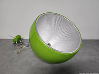Side view of green spherical metal ceiling light with white interior and suspension cord.