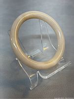 Side view of round natural jade bangle showing smooth polished surface and tan color