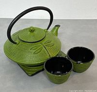 Green cast iron dragonfly kettle with two matching cups, shown from front angle