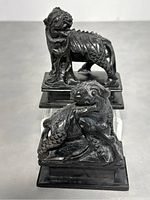 Pair of black stone Foo Dog statues, one standing and one crouching, placed side by side on a flat surface.