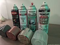 Four new spray paint cans arranged vertically with caps placed below each can, showing the colors and brand labels clearly.