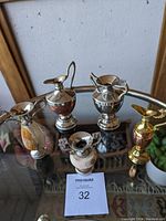 Five mini urns made from different metals and marble arranged on a glass table showing size and variety.