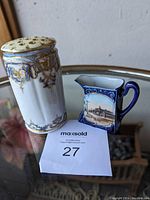 Two-piece lot showing the antique porcelain talc powder shaker and the mini German porcelain creamer placed side by side on a glass table