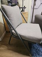 Side view of the chair showing the gray seat and back cushions, black metal frame angled design.