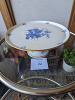 View of top surface showing hand painted blue floral design and gold rim