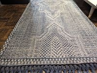 Full view of indigo hallway runner carpet showing geometric and tribal patterns with fringes at one end.