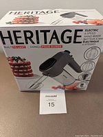 Photo of the original box for the Heritage 6-speed electric hand mixer showing front and side images, highlighting key features like beaters and dough hooks.