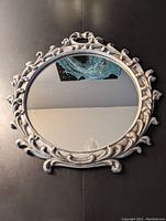 Front view of the round Romanesque mirror with visible intricate scroll and leaf design on silver/pewter toned frame