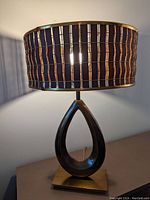 Front view of the Mid Century Modern table lamp showing the teak slat shade and teardrop shaped brass base.
