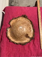 Top-down view of the 12-inch burled maple wood bowl showing polished interior and natural bark edges, placed on a red cloth with measuring stick alongside.