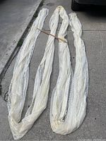 Full length photo of the coiled lace material showing its length and delicate texture, with a wooden yardstick for scale.