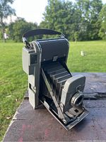 Side angle showing the Polaroid Land Camera Model 80 opened with extended bellows on outdoor surface.