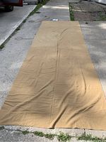 Full view of the laid out partial bolt of camel hair wool flannel fabric on concrete surface, showing overall size and color.