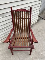 Front view of antique splint ash porch chair with bent ash splints and red painted frame on concrete surface.