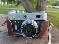 Front view of FED 3 35mm Soviet camera with lens, showing metal body and brown leather case with strap.