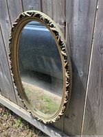 Side angled view of oval gesso mirror showing the decorative foliate frame and overall shape.