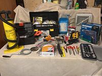Wide shot of the entire lot laid out on a beige cloth, showing tools, tool boxes, air pump, space heater and various hand tools.