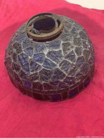 Top view of stained glass lamp shade showing dark blue glass mosaic and metal attachment ring with screw clamp.