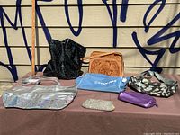 Full lot view showing seven various purses and bags on table with wall background
