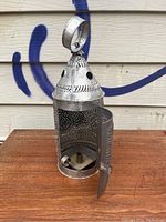 Front angle of the punched tin candle lamp showing the door open and interior candle holder.