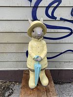Front view of the 42-inch tall resin bunny rabbit figurine in yellow raincoat and boots holding blue umbrella