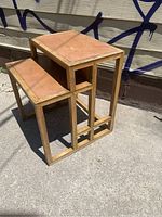 Full view of the side table showing the two-tier leather inlaid surfaces with brown wooden frame and geometric open design sides.