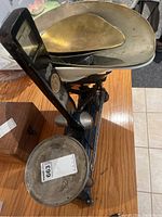 View showing the black cast iron base, metal weighing pan, smaller metal bowl, and balance beam.