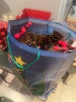 Blue star-themed gift bag filled with large natural pine cones and red berry picks, shot from above.