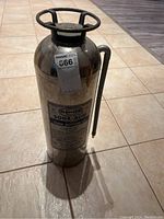 Full view of the chrome soda-acid fire extinguisher with label and attached hose.