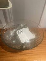 Wide view of the large clear crystal punch bowl showing the curved rim and pattern on the side. The bowl is placed on a wooden surface.