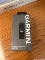 Garmin Vivofit 4 fitness tracker in gray retail box, front view showing product image and branding.