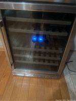 Front view of closed wine fridge showing stainless steel trim and glass door.