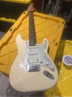 Full-body view of off-white guitar lying on yellow storage bins