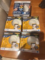 Five boxes of Halo Home 4 inch LED pot lights on table.