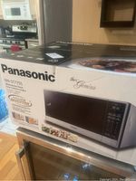 Box of Panasonic Genius microwave oven model NN-ST775S with features and picture of unit.